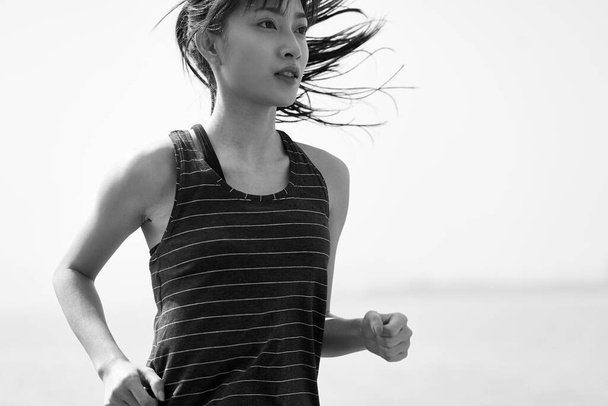 fiatal ázsiai nő futás a tenger mellett, fekete-fehér - Fotó, kép