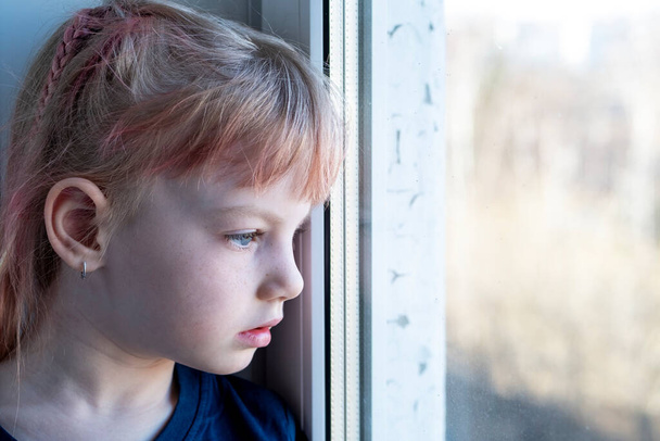 Child sits on a windowsill with a mobile phone - Foto, Imagem