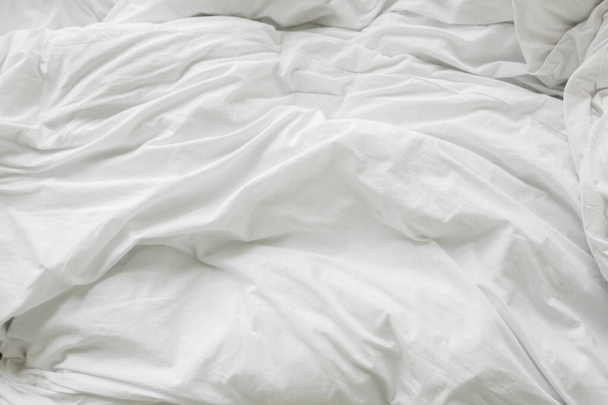 wrinkle messy blanket and white pillow in bedroom after waking up in the morning, from sleeping in a long night, details of duvet and blanket, an unmade bed in hotel bedroom with white blanket. - Foto, Imagem