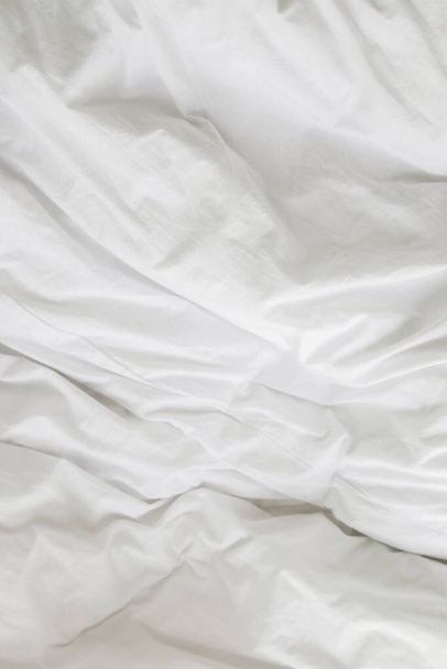 wrinkle messy blanket and white pillow in bedroom after waking up in the morning, from sleeping in a long night, details of duvet and blanket, an unmade bed in hotel bedroom with white blanket. - Фото, зображення