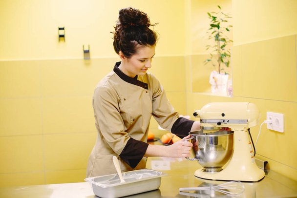 Female confectioner working with mixer - Foto, afbeelding