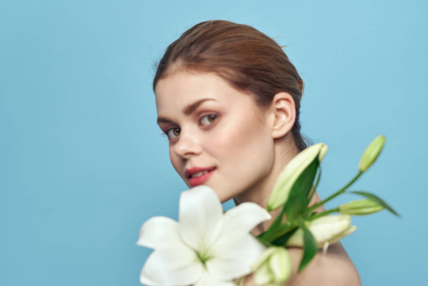 Woman with white flower on blue background cropped view of naked shoulders - Фото, зображення