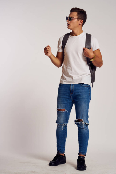 ein Mann mit Rucksack auf dem Rücken in Jeans-T-Shirt, Turnschuhen und Brille im Gesicht - Foto, Bild