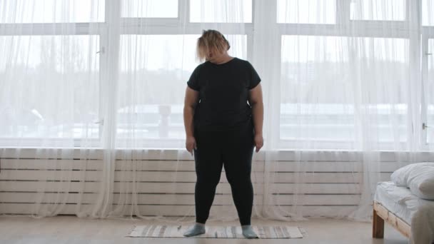 Une grosse femme fait des exercices à la maison - réchauffant son cou - Séquence, vidéo