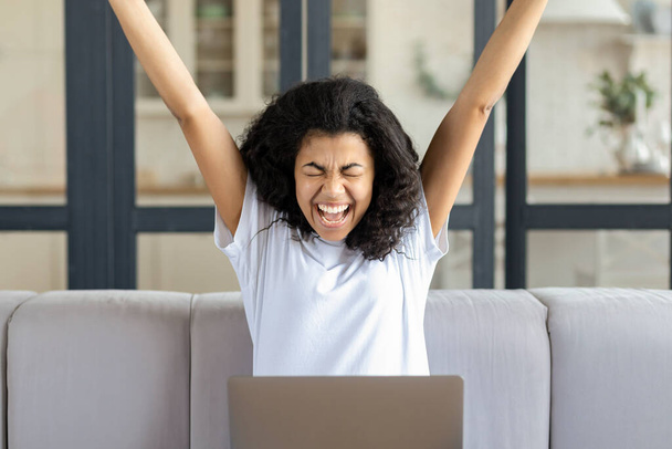 Excited young female with laptop sitting at home on the couch received an email with great news - Fotoğraf, Görsel