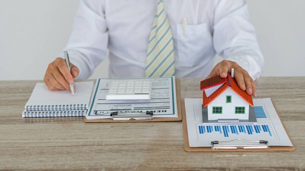 Type de maison agent immobilier et calculatrice avec documents contractuels sur la table dans le bureau. - Photo, image