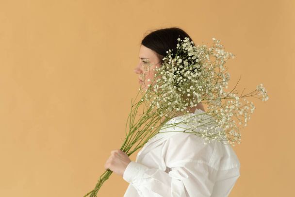 портрет молодої красивої жінки в студії з білими квітами на жовтому тлі
 - Фото, зображення