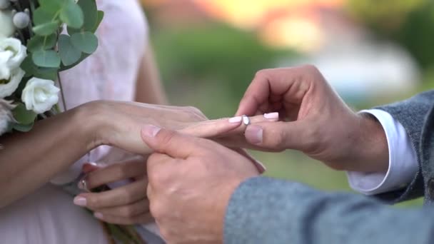 Groom puts ring on brides finger during wedding ceremony, bride holds bouquet - Footage, Video