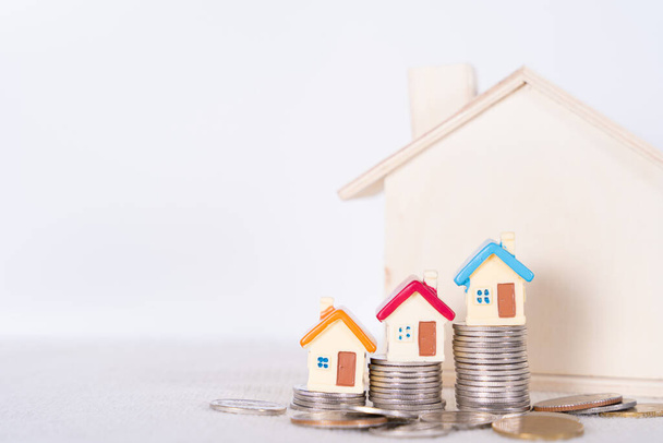 Haus und Stapel Münzen isoliert grauen Hintergrund. Immobilieninvestitionen und Hypothekenfinanzierung. - Foto, Bild