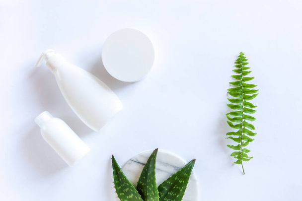 Set of Cosmetic containers, dispenser and fresh green aloe leaves on white background. - Photo, Image