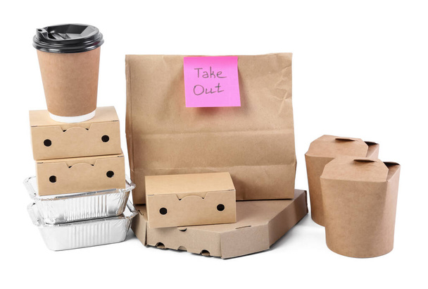 Paper bag with sticker TAKE OUT, containers for food and cup on white background - Photo, Image
