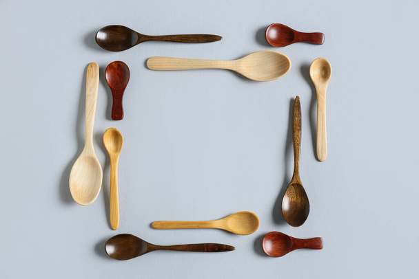Frame made of wooden spoons on light background - Photo, image