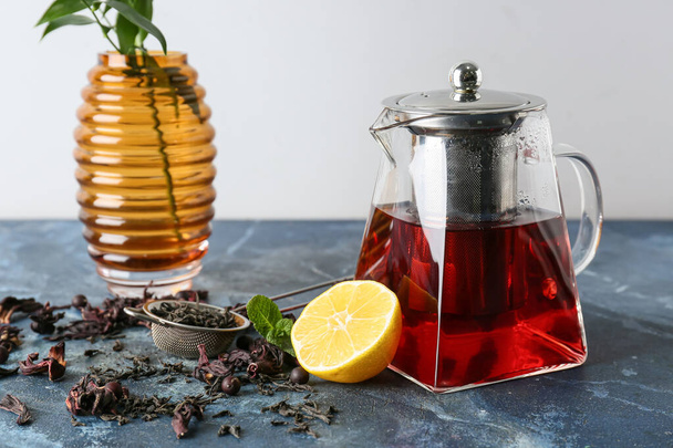 Чайник вкусный чай гибискус с лимоном на цветном фоне - Фото, изображение