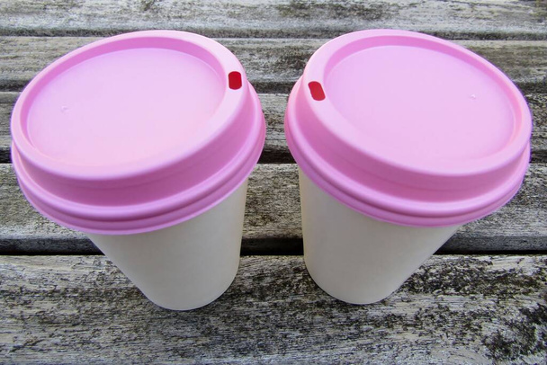 Δύο κύπελλα καφέ λευκό χαρτί με ροζ καπάκια σε ξύλινο τραπέζι - Φωτογραφία, εικόνα