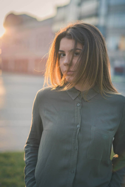 A vertical shot of a pretty female in casual clothes posing outdoors during sunse - Foto, immagini