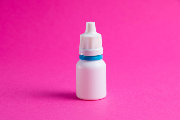 Bílá láhev s nosem nebo oční kapky na růžovém papírovém pozadí. Medicína na pozadí s kopírovacím prostorem - Fotografie, Obrázek