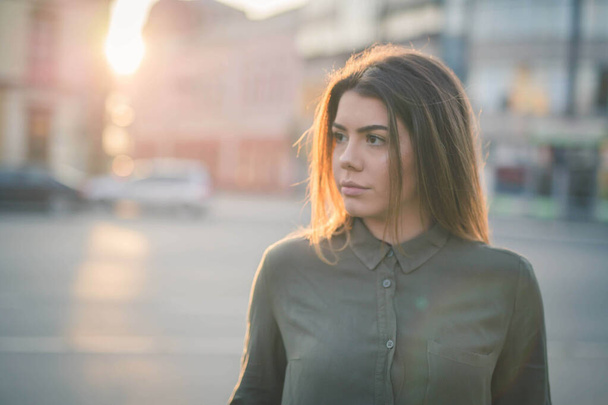 A shallow focus shot of a beautiful Caucasian woman wearing a grey blouse, posing outdoors - Foto, Bild