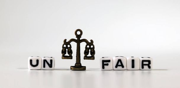 Miniature scale between cube with word 'UN' and cube with word 'FAIR'. The concept of a fair society. - Photo, Image