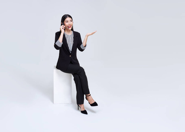 Smiling Asian businesswoman customer support phone operator isolated over gray background. call center and customer service concept. - Foto, immagini