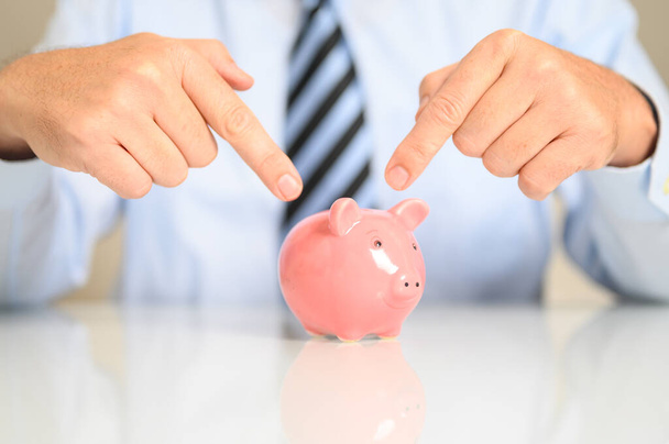 A closeup of a businessman pointing to a piggy bank - Fotografie, Obrázek