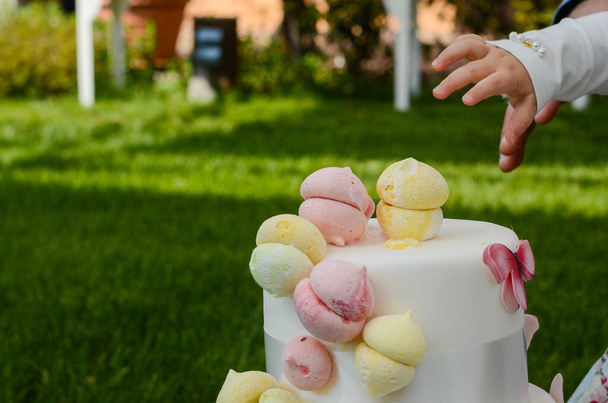 Een klein meisje plukt een meringue uit haar verjaardagstaart - Foto, afbeelding