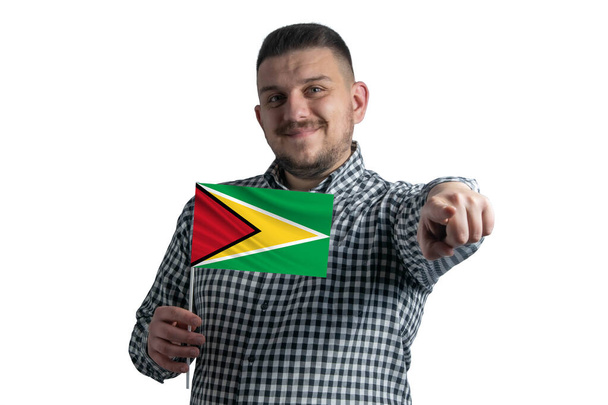 Blanc tenant un drapeau de Guyane et pointe vers l'avant devant lui isolé sur un fond blanc. - Photo, image
