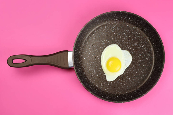 Fried egg in a frying pan on a pink background - Photo, Image