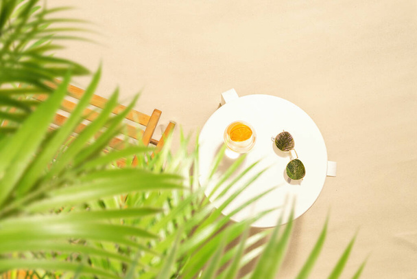 Beach holidays. Orange juice and sunglasses on the table of outdoors cafe under palm tree branches. Top view - 写真・画像
