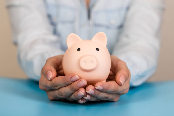 Sparschwein in der Hand auf blauem Hintergrund, Platz für Text. Finanzen, Geld sparen - Foto, Bild