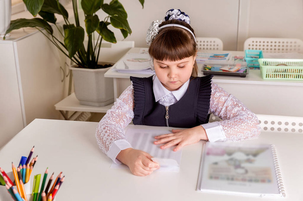 A girl pupul  sits at  a desk in the classroom and reads a book. Back to school concept - Фото, зображення