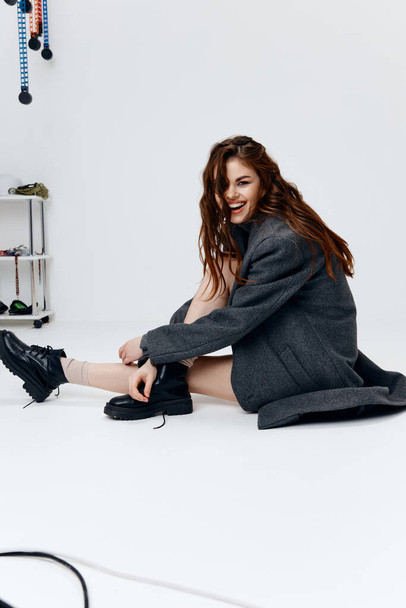 gelukkig vrouw model in grijs jas en laarzen op lichte achtergrond  - Foto, afbeelding