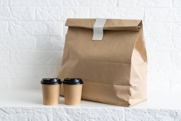 Set de envases de comida rápida. Tazas de café de papel en el titular, caja de alimentos, bolsa de papel marrón en la mesa - Foto, imagen