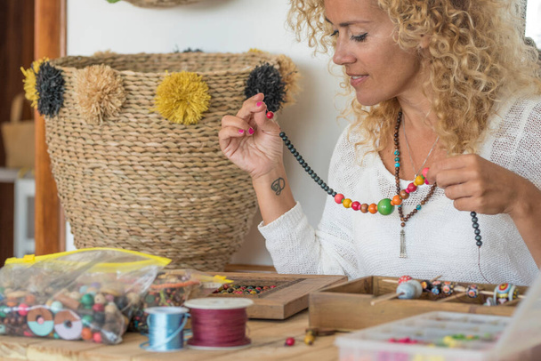 Mladá dospělá žena vyrábí perle šperky doma u stolu - Fotografie, Obrázek