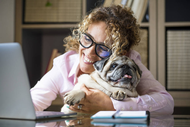 Woman work at home with laptop computer in smart working business modern job activity with her adorable best friend pug dog together with love and friendship - Photo, image