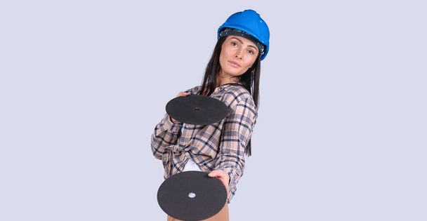 Banner, long format isolated gray background. Serious brunette woman showing Hard woman holding two disks for radial grinder tool. Repair woman, force. High quality photo - Foto, Imagem