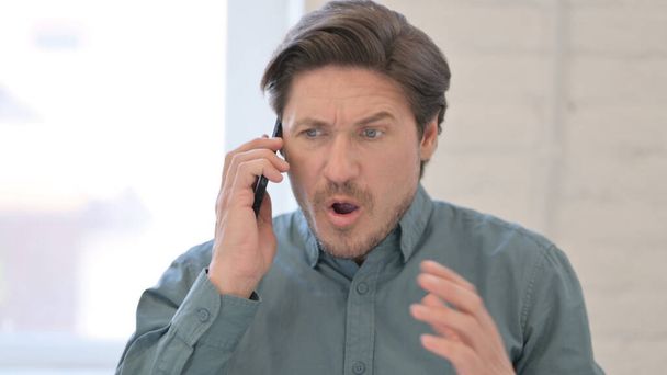 Retrato de hombre de mediana edad agresivo enojado en el teléfono inteligente - Foto, imagen