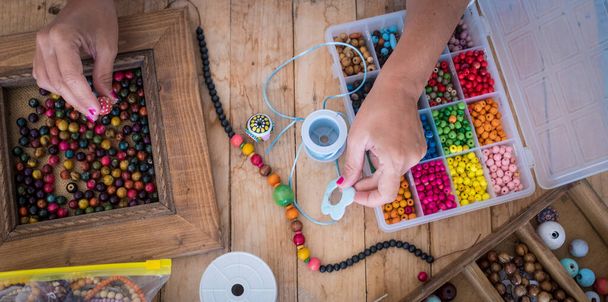 Visão superior da mulher fazendo jóias contas acessórios com cordas coloridas  - Foto, Imagem