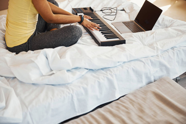 Female musician playing synth and using notebook at home - Foto, Bild