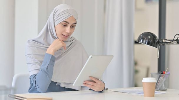 オフィスでタブレットでビデオ通話を行う若いアラブ人女性  - 写真・画像