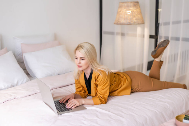 Happy casual beautiful woman working on a laptop sitting in the house. - Foto, imagen