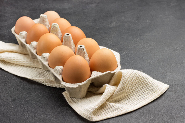 Brown chicken eggs in carton container. Copy space. Black background.  Top view - Photo, Image