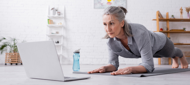 volwassen vrouw doen plank en kijken naar laptop, banner - Foto, afbeelding