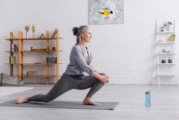 side view of flexible mature woman practicing yoga on mat  - Valokuva, kuva