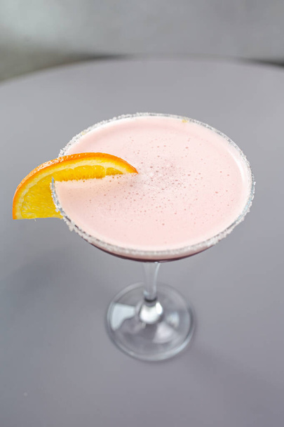 roter Cocktail mit Orange auf grauem Hintergrund. - Foto, Bild