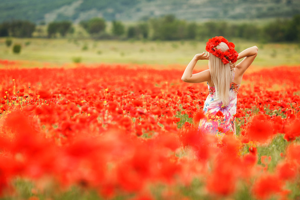 Beautiful young blonde woman in red bright poppy field. - Foto, afbeelding