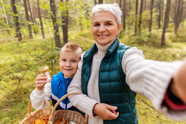 grandmother with grandson taking selfie in forest - Фото, зображення