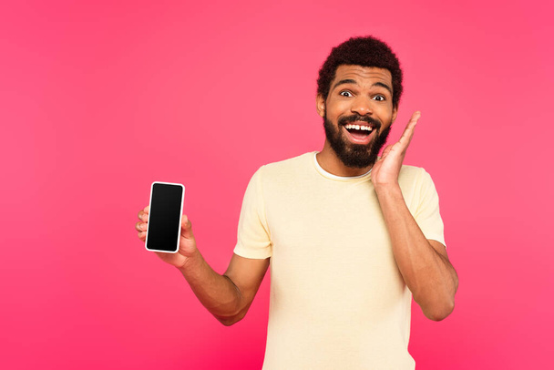 excited african american man holding smartphone with blank screen isolated on pink - Фото, изображение