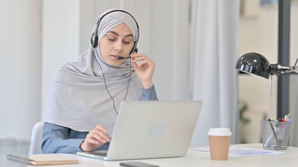 Junge Araberin mit Laptop spricht über Headset  - Foto, Bild
