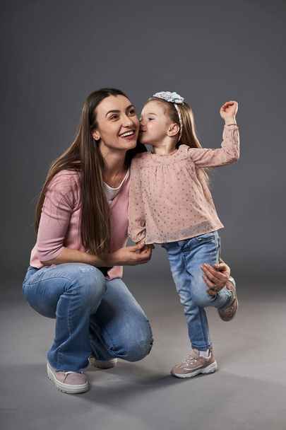 Young mother with her preschool little daughter on gray background - Foto, Bild