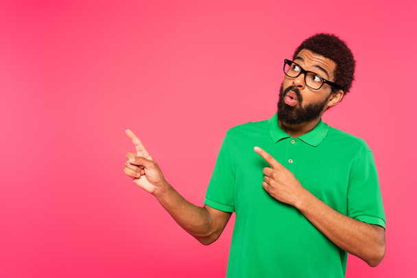 shocked african american man in glasses pointing with fingers isolated on pink - Φωτογραφία, εικόνα